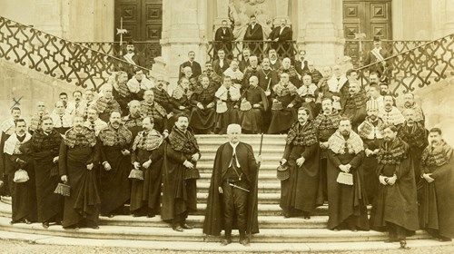 Os professores doutorados — então chamados lentes — das faculdades de Teologia, Direito, Medicina, Matemática e Filosofia Natural, nas escadarias da Via Latina, na Universidade de Coimbra, após as cerimónias de abertura do ano letivo. Sidónio Pais, doutor em Matemática desde 1898, é o primeiro à esquerda, na segunda fila; tornou-se catedrático em 1904. Ao seu lado encontra-se Bernardino Machado, seu antigo professor da cadeira de Antropologia. Reconhecem-se, entre outros: à esquerda do mestre-de-cerimónias com o seu bastão, ao centro, Afonso Costa; a seguir, António Guimarães Pedrosa; à direita daquele mestre, José Alberto dos Reis.