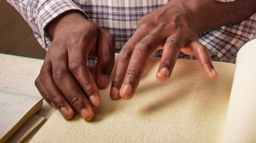 Visitante cego lendo o folheto do Museu em Braille.