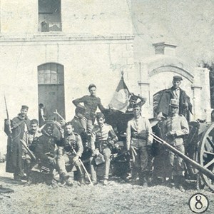 Bilhete-postal com imagem fotomecânica, registando um grupo de revoltosos junto ao hospital de sangue, estrutura temporária criada durante a revolução do 5 de Outubro. No verso, a inscrição: «Recordação do 1.º Anniversario da Republica Portugueza».