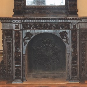 Este fogão de sala permanece na então chamada Sala de Estado do Palácio da Cidadela de Cascais, fazendo parte da decoração mais antiga encomendada por D. Maria Pia e D. Luís. Em baixo, na boca da lareira, fundido em ferro, encontra-se o escudo da Casa de Bragança, à esquerda, e a cruz da Casa de Saboia, à direita, alusões aos monarcas. Os escudos estão ligados pelo colar da Ordem Militar da Torre e Espada.